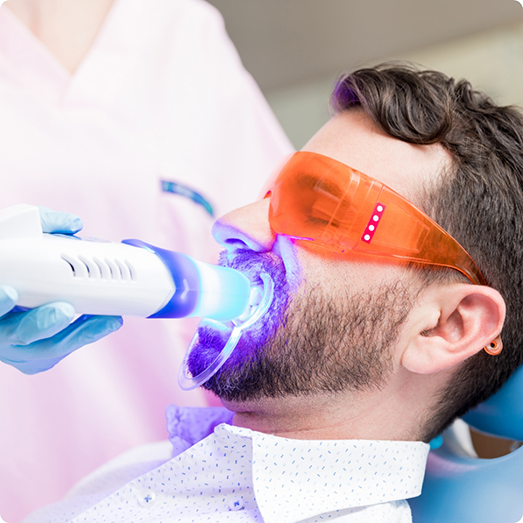 Man in dental chair having teeth whitening performed