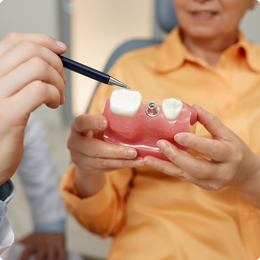 Close up of a patient holding a dental implant model