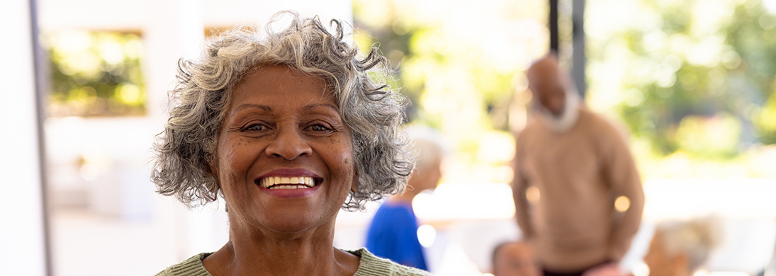 Senior woman with curly hair smiling after replacing missing teeth in Fredericksburg