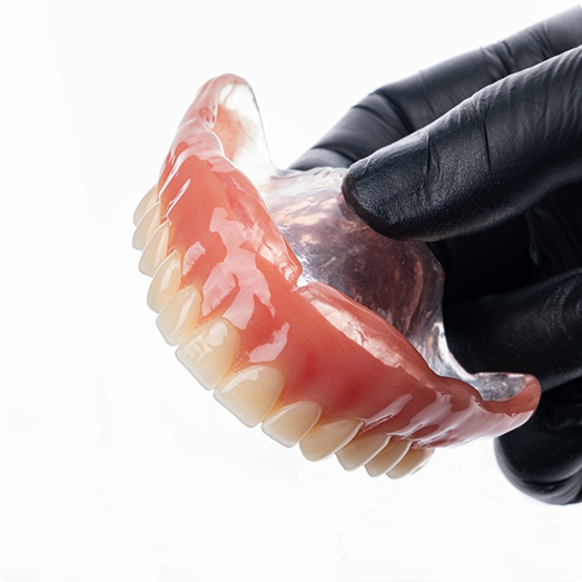 Gloved hand holding a full denture