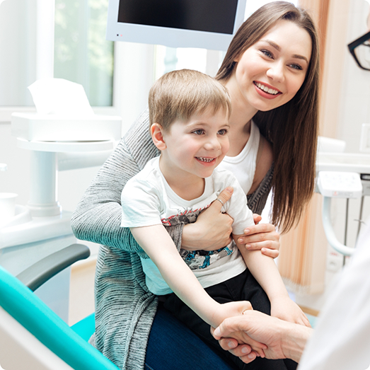 Mother in dental chair holding her child