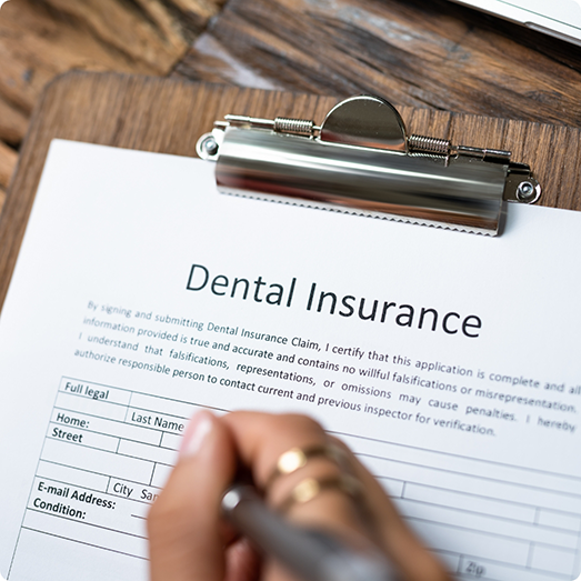Filling out dental insurance form on a clipboard