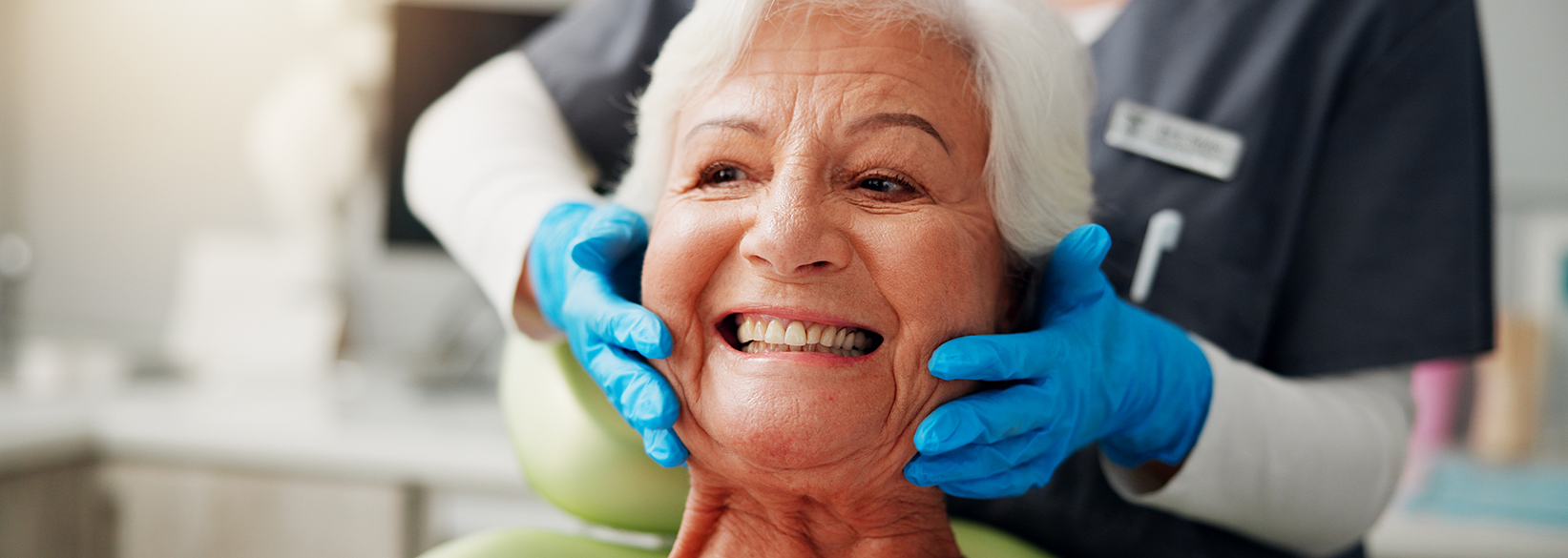 Senior woman smiling in dental chair after restorative dentistry in Fredericksburg