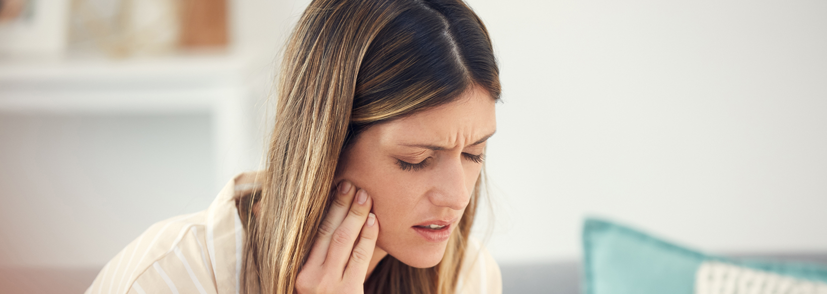 Concerned woman rubbing her jaw in pain before tooth extractions in Fredericksburg
